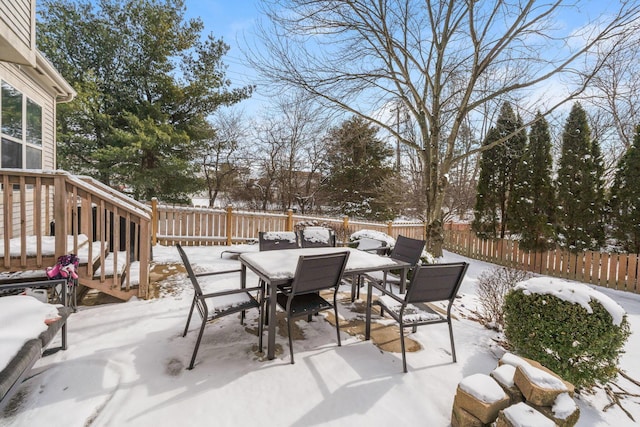 snow covered patio featuring a fenced backyard and outdoor dining area