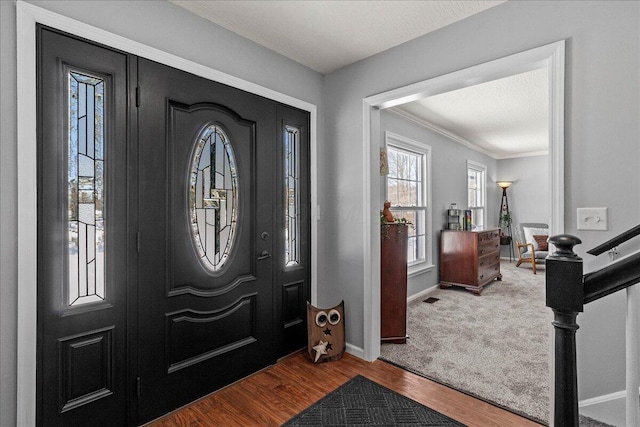 foyer entrance featuring visible vents, baseboards, wood finished floors, and ornamental molding