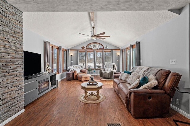 living area featuring a ceiling fan, lofted ceiling with beams, wood finished floors, and a textured ceiling