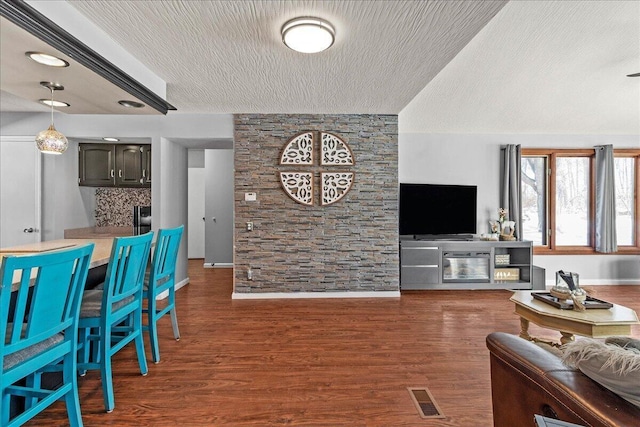 living room with wood finished floors, visible vents, and a textured ceiling