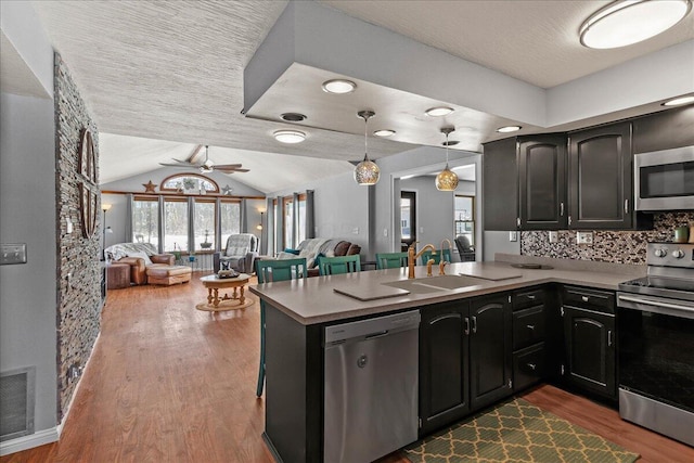 kitchen with visible vents, dark wood finished floors, lofted ceiling, stainless steel appliances, and open floor plan