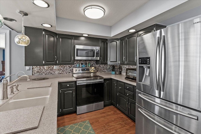 kitchen with dark wood finished floors, a sink, decorative backsplash, light countertops, and appliances with stainless steel finishes