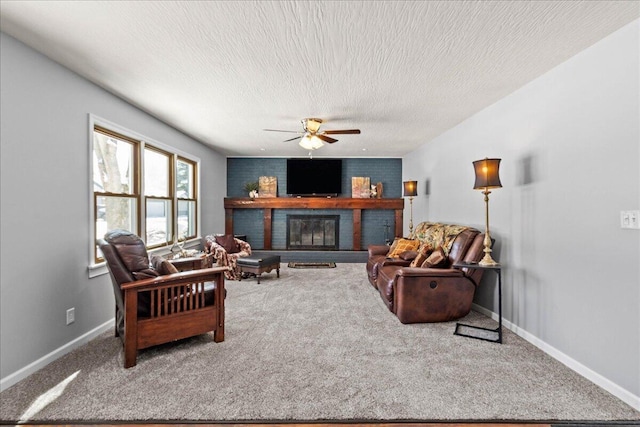 carpeted living room featuring ceiling fan, a brick fireplace, a textured ceiling, and baseboards