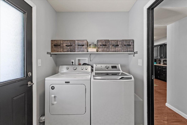 laundry area featuring baseboards, separate washer and dryer, wood finished floors, and laundry area