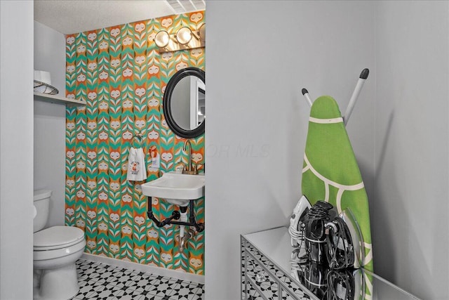 bathroom featuring wallpapered walls, tile patterned floors, toilet, and baseboards