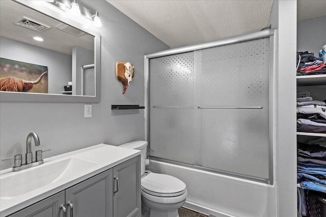 full bath featuring visible vents, toilet, vanity, enclosed tub / shower combo, and a spacious closet