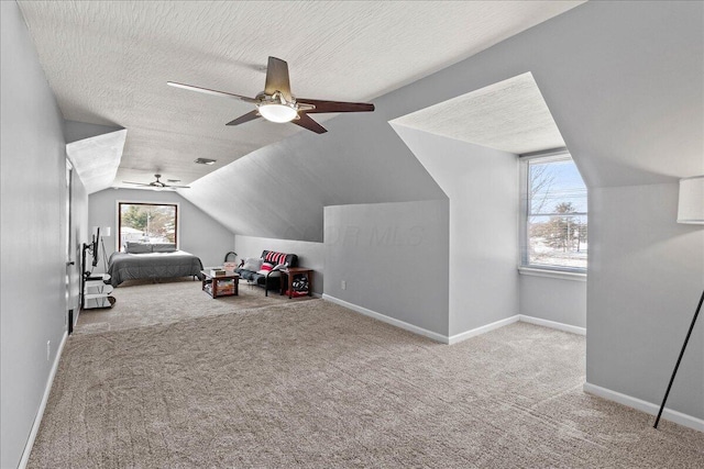 carpeted bedroom featuring a textured ceiling, lofted ceiling, baseboards, and a ceiling fan