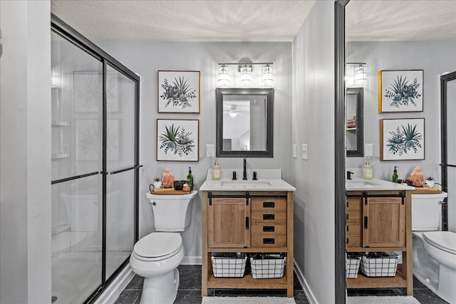 full bathroom with a sink, toilet, two vanities, and a shower stall