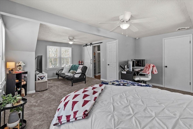 bedroom featuring visible vents, a textured ceiling, a barn door, carpet, and baseboards