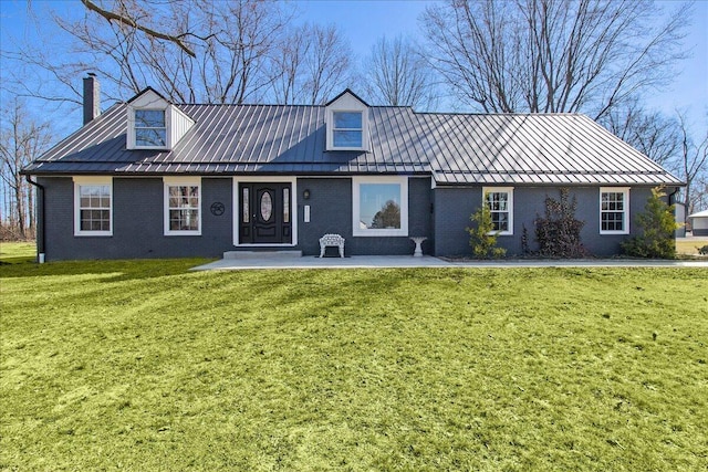 view of front facade with brick siding, a front lawn, a chimney, metal roof, and a standing seam roof