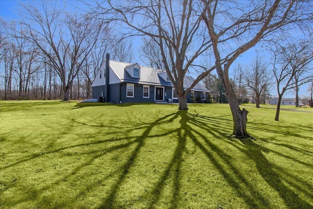 exterior space featuring a lawn, a chimney, and metal roof