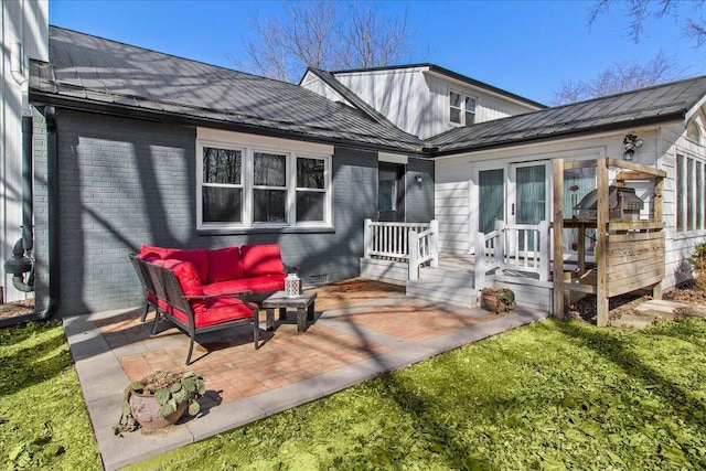 rear view of property featuring metal roof, brick siding, outdoor lounge area, and a patio area