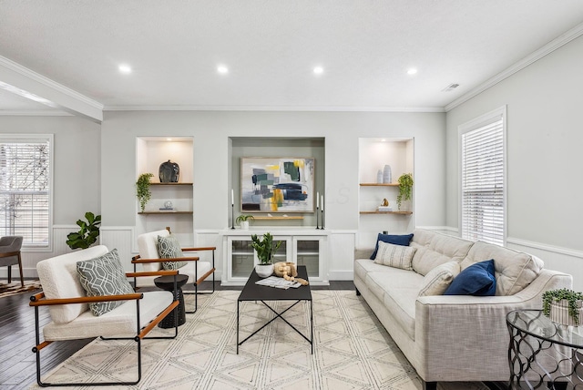 living room with a wealth of natural light, a wainscoted wall, and crown molding