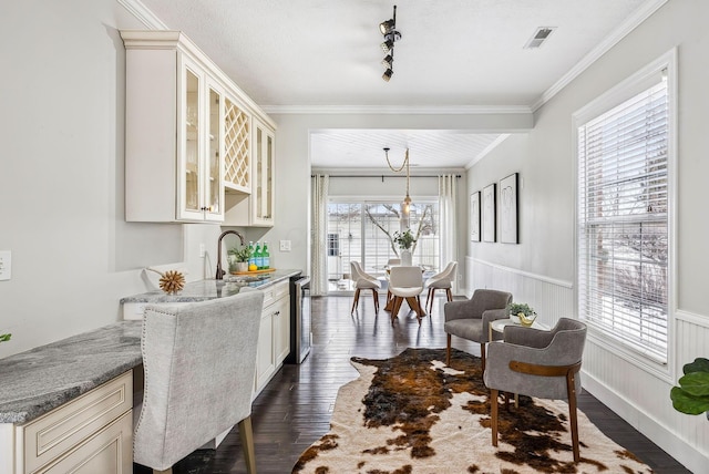 dining area with visible vents, a wainscoted wall, dark wood-style flooring, crown molding, and a textured ceiling