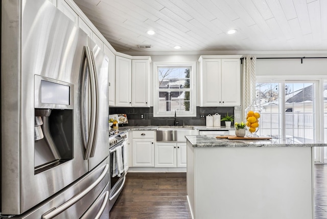 kitchen featuring a kitchen island, a sink, white cabinetry, appliances with stainless steel finishes, and light stone countertops