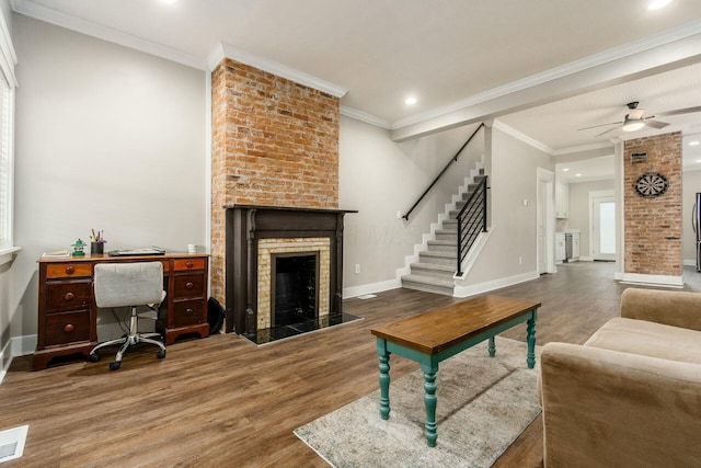 living room featuring dark wood-type flooring, a fireplace, ornamental molding, and ceiling fan