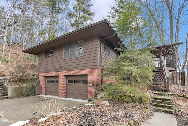 view of home's exterior with a garage, driveway, stairs, and brick siding