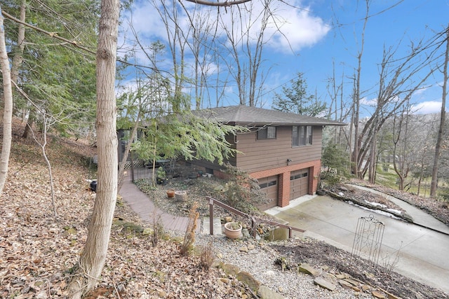 view of property exterior featuring a garage, driveway, and brick siding