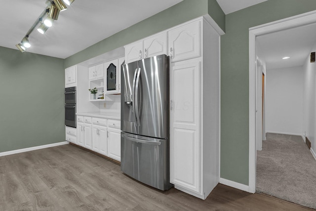 kitchen with baseboards, white cabinets, light countertops, light wood-type flooring, and stainless steel fridge with ice dispenser