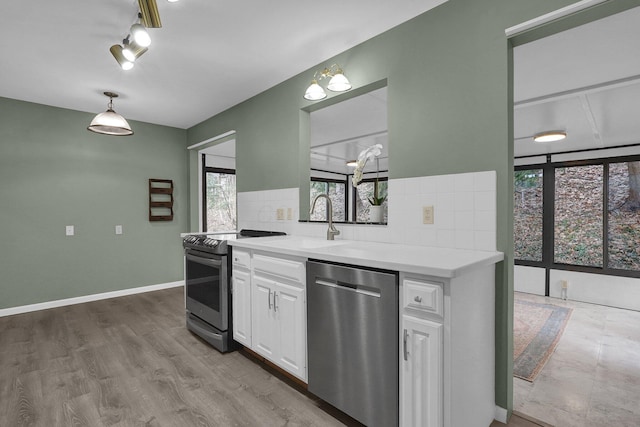 kitchen with tasteful backsplash, light countertops, appliances with stainless steel finishes, white cabinetry, and wood finished floors