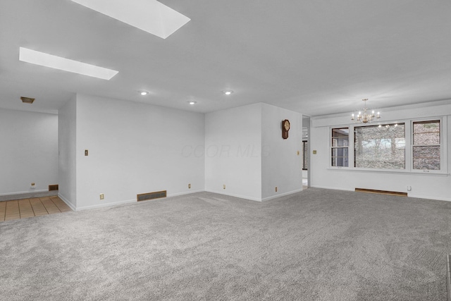 spare room featuring a skylight, visible vents, baseboards, carpet flooring, and a notable chandelier