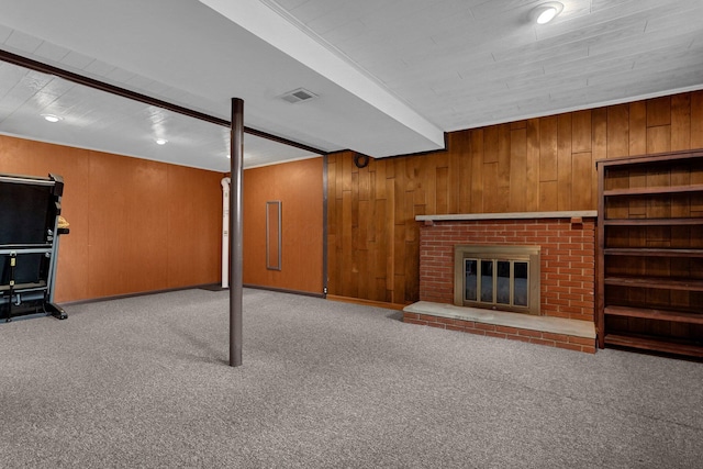 finished below grade area featuring a brick fireplace, light colored carpet, wood walls, and visible vents