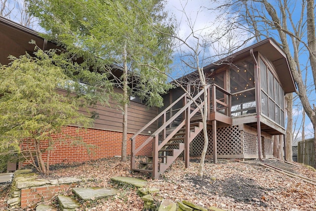 view of property exterior featuring stairs, brick siding, and a sunroom