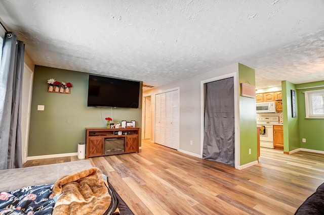 bedroom featuring light wood-type flooring, ensuite bath, multiple closets, and a textured ceiling