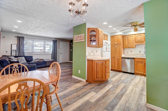 kitchen featuring light wood-type flooring, hanging light fixtures, decorative backsplash, and dishwasher