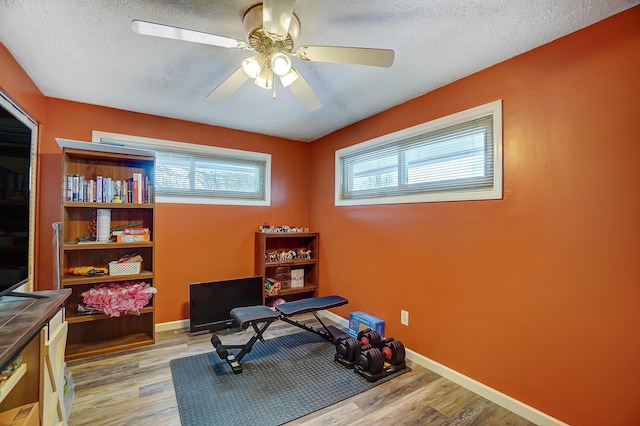 exercise area featuring light hardwood / wood-style floors, ceiling fan, and a textured ceiling