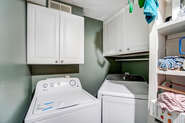 washroom featuring washing machine and dryer, cabinets, and a textured ceiling