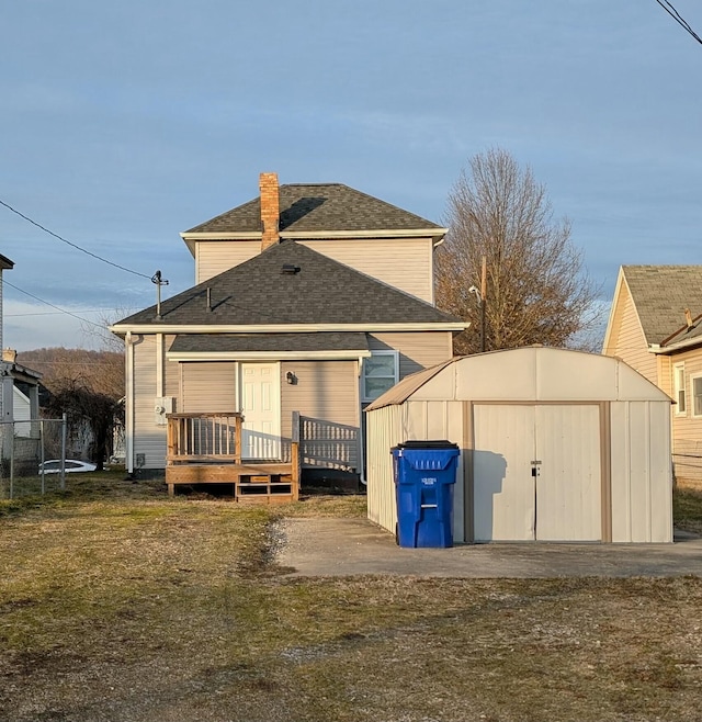 rear view of house featuring a yard, a wooden deck, and a storage shed