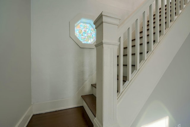 stairs with ornate columns and wood-type flooring