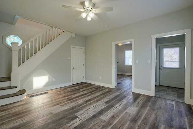 unfurnished living room with ceiling fan, dark wood-type flooring, and plenty of natural light