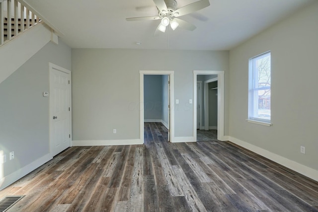 interior space featuring ceiling fan, dark wood-type flooring, a walk in closet, and a closet