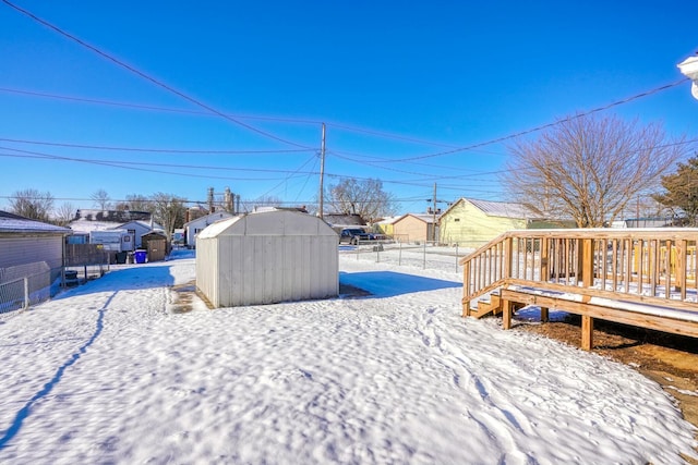 snowy yard with a storage unit and a wooden deck