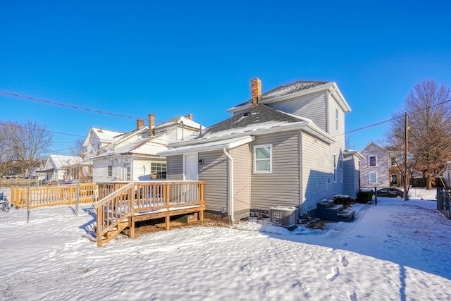 snow covered back of property featuring a wooden deck