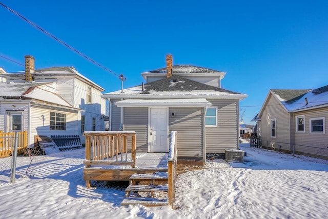 snow covered back of property with a deck and cooling unit