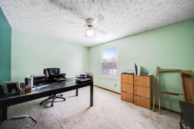 office space featuring baseboards, a textured ceiling, a ceiling fan, and light colored carpet