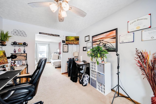 office space featuring light carpet, ceiling fan, and a textured ceiling