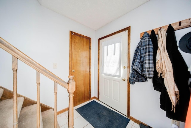 doorway featuring light tile patterned flooring, a textured ceiling, and stairs