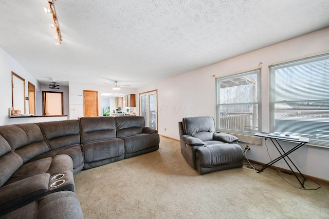 living room with a textured ceiling, baseboards, and light colored carpet