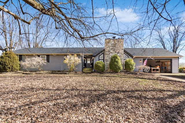 view of front of property featuring an attached garage, driveway, and a chimney