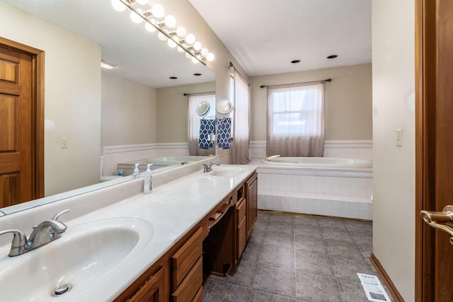 bathroom featuring double vanity, visible vents, a sink, and a bath