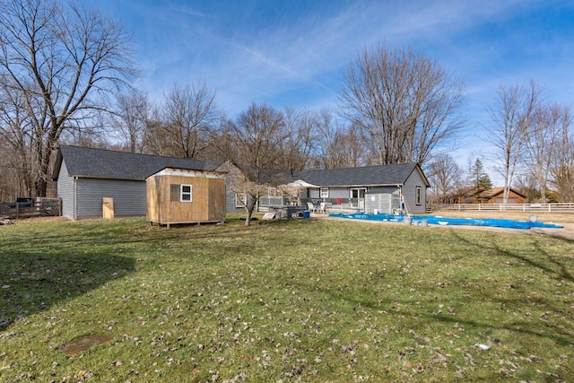 view of yard featuring a storage shed, an outdoor structure, fence, and a fenced in pool