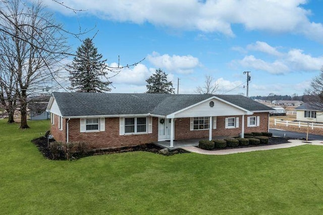 single story home featuring covered porch, brick siding, and a front yard