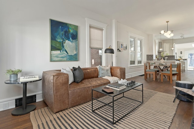 living room with a chandelier, baseboards, wood finished floors, and a healthy amount of sunlight