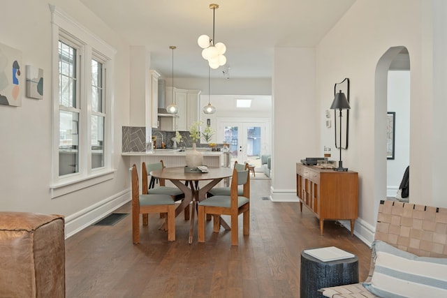 dining space featuring arched walkways, visible vents, baseboards, french doors, and dark wood finished floors