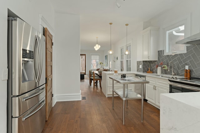 kitchen with white cabinets, wall chimney range hood, appliances with stainless steel finishes, and dark wood finished floors