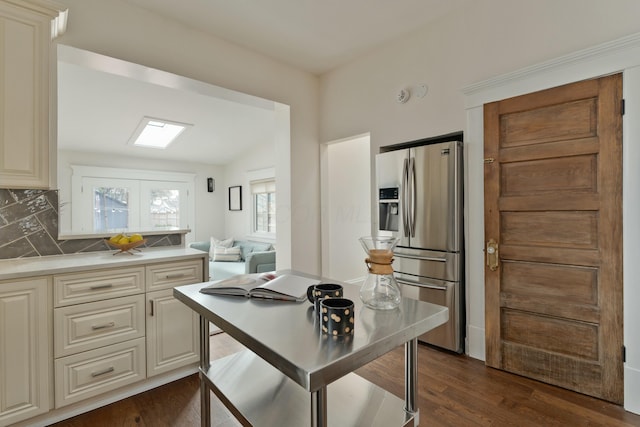 kitchen featuring stainless steel fridge with ice dispenser, light countertops, cream cabinetry, decorative backsplash, and dark wood finished floors